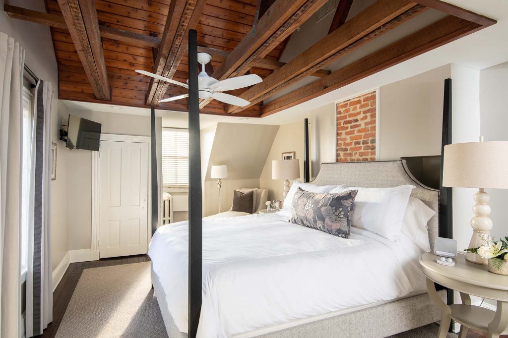 An airy four-poster bed allows exposed brick to show, adding character and a touch of romance, replacing outdated furnishings. 