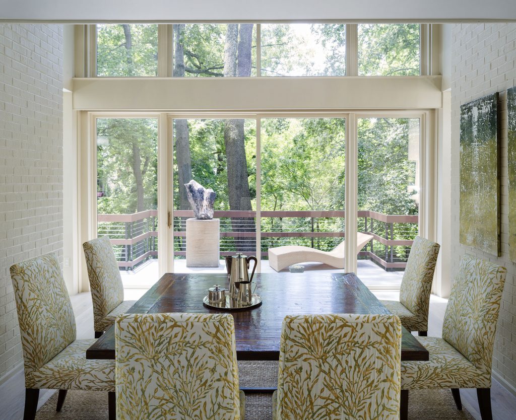 The dining room overlooks the woods and fossil scultpure; the wrap-around deck is “another circular rhythm,” says architect Donald Lococo.  