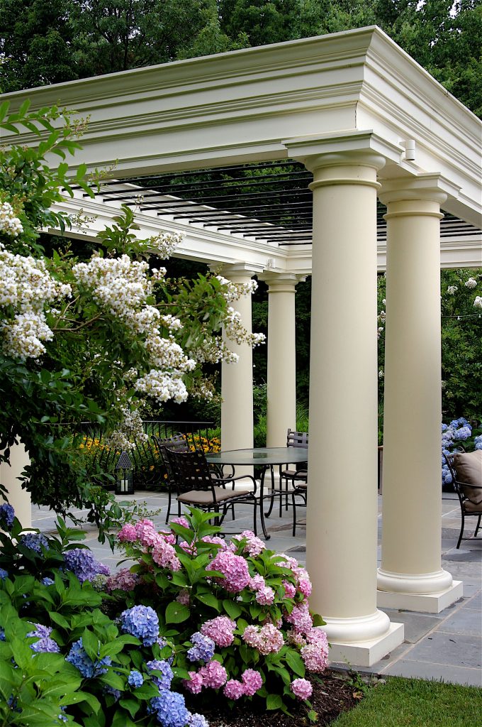 A classical pergola is adorned with climbing blooms.