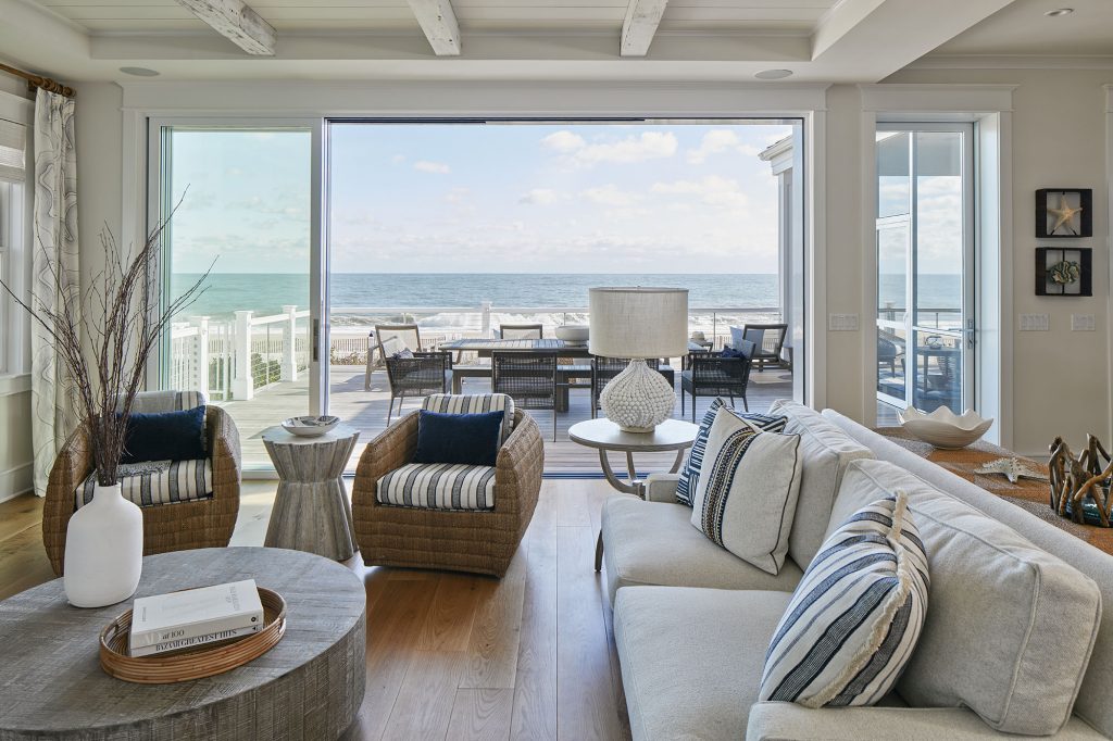 A cozy seating area has a window wall that opens to an expansive deck and endless sea.