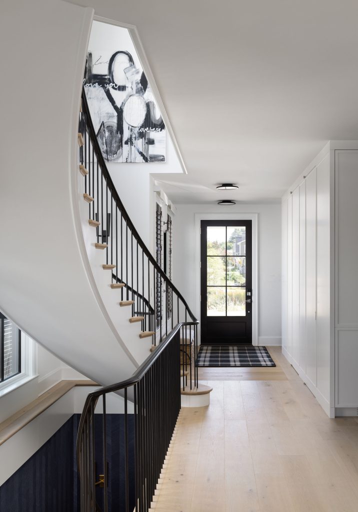 An elliptical stair connects all three levels, inviting discovery; walls painted Diamond White by Benjamin Moore reflect light, and contrast vividly with black trimwork. Photo by Jenn Verrier