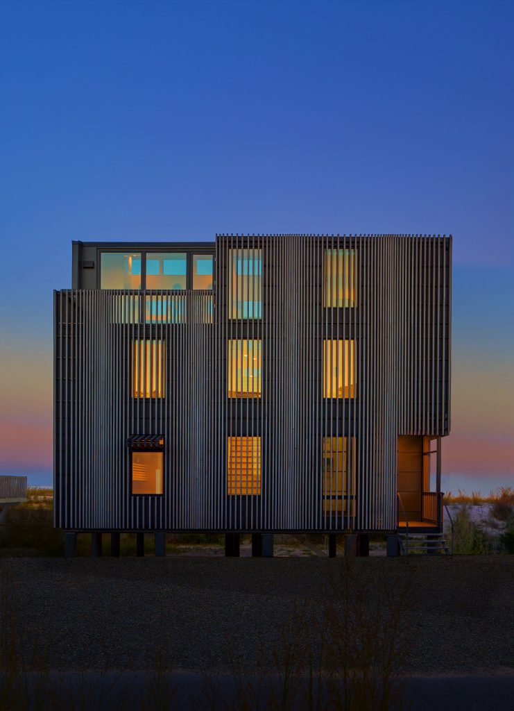 This home’s exterior, composed of vertical “fins” made of shou sugi ban, is inspired by dune fencing. As the sun moves across the sky, they create ever-shifting shadows throughout the interior.