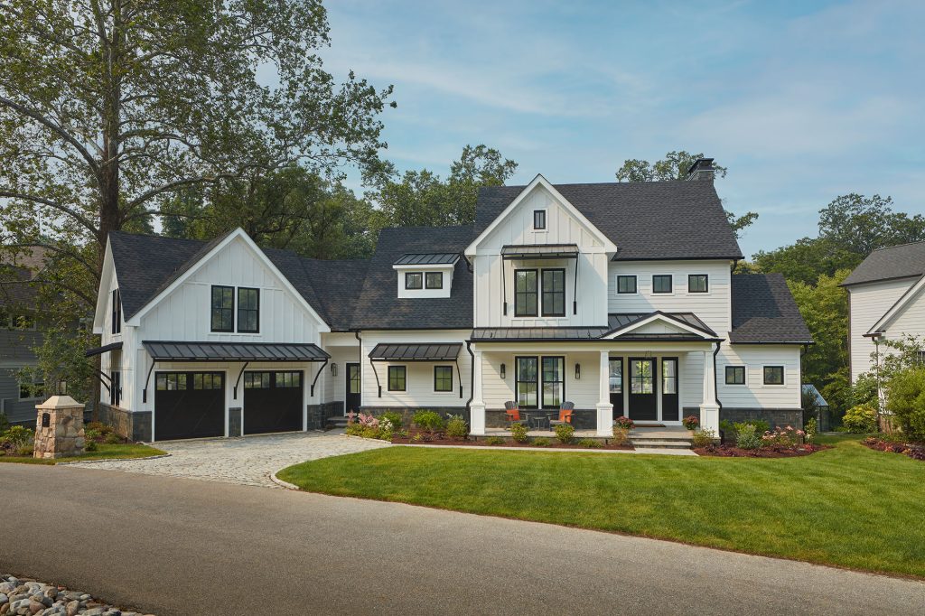 This well-appointed farmhouse has traditional front gables but modern elements, such as custom doors and expansive windows of different sizes.