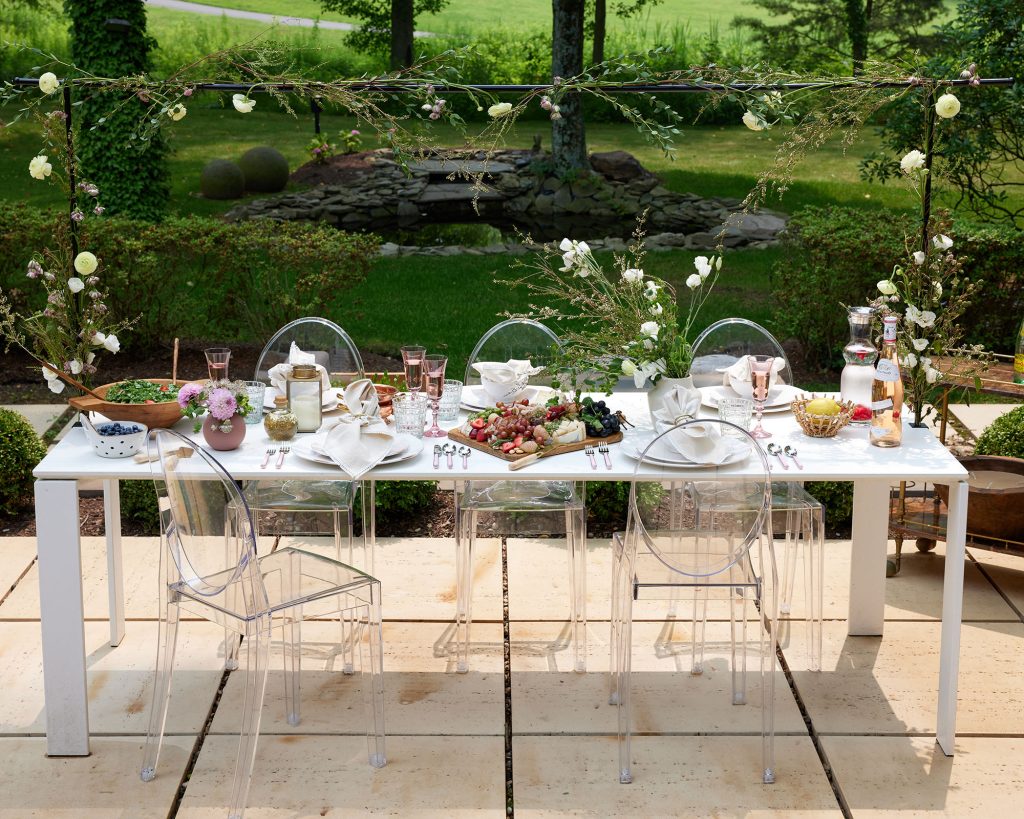 A lush table setting reflects the layers of greenery and subtle colors in the summer landscape.
