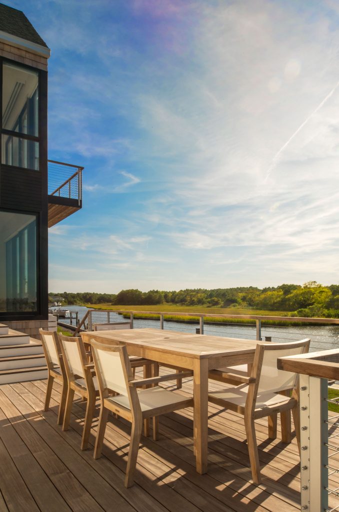 Natural decking, lots of glass walls, and minimal cable railing are all that separates  this home from the waters just beyond.